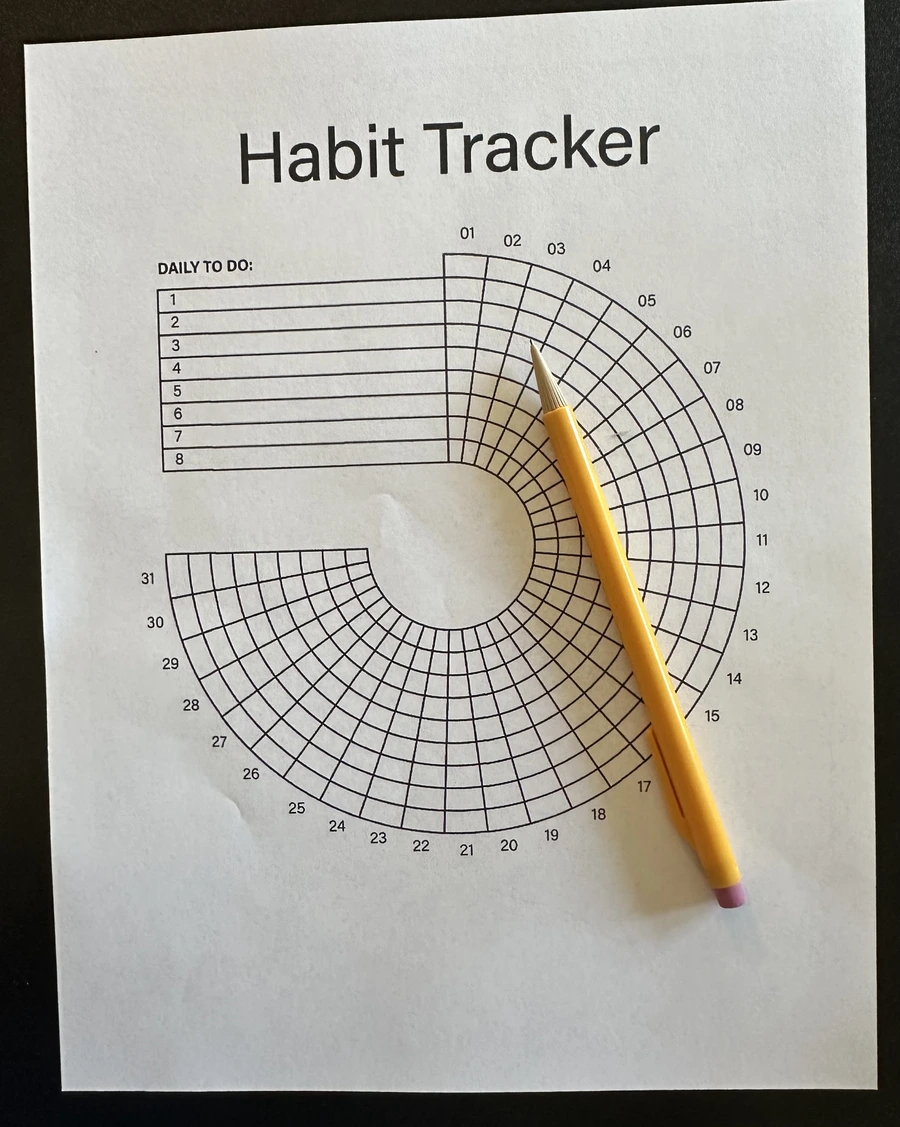 A printed spiral habit tracker template with a pencil resting on it